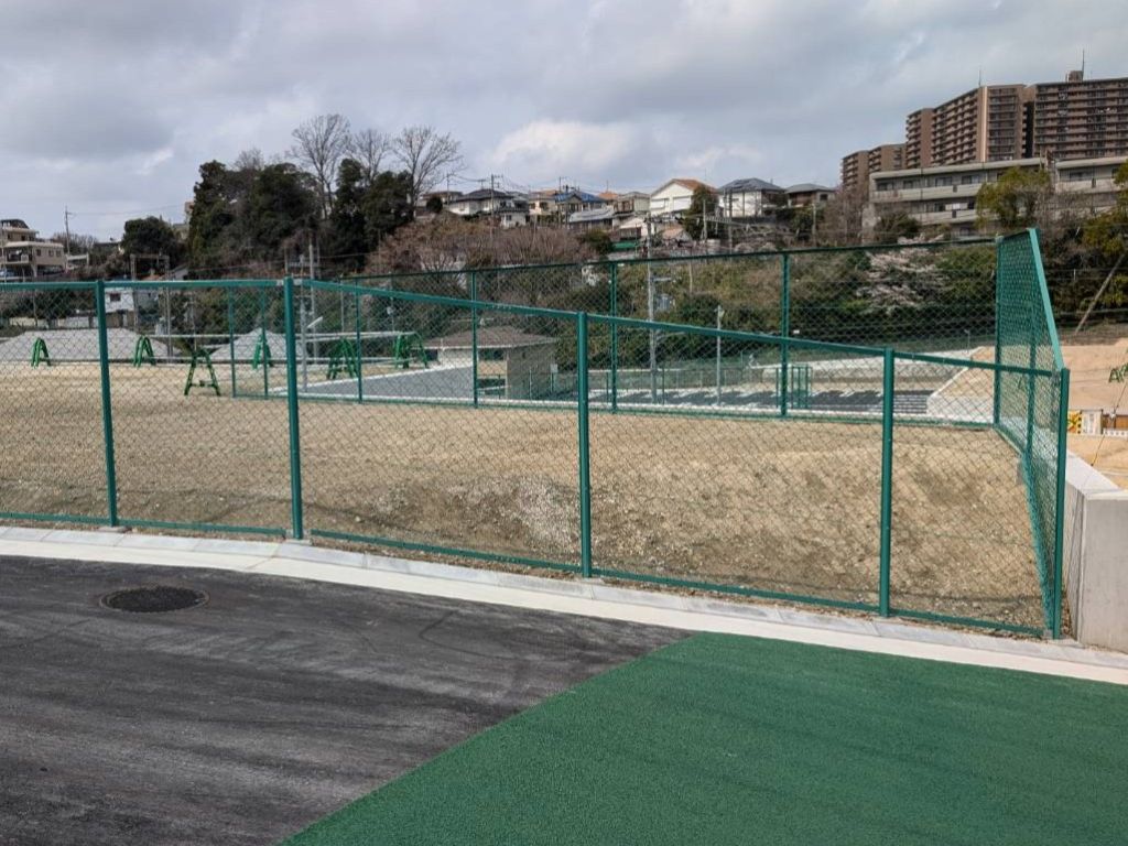 フェンスにワイヤーを取り付ける作業員